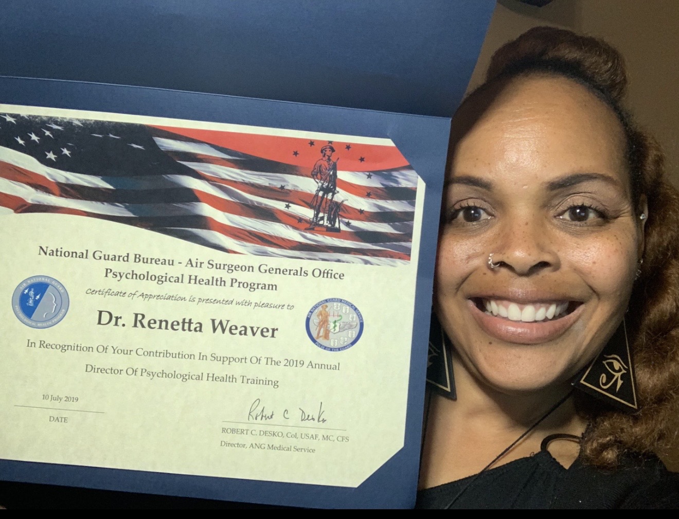 Dr. Renetta Weaver beside a National Guard Bureau Certificate of Appreciation.